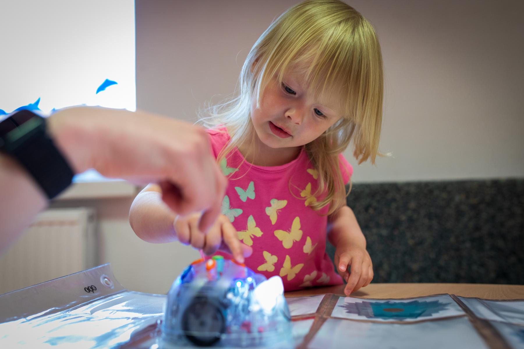 Kindergartenkind schaut sich eien Blue-Bot an