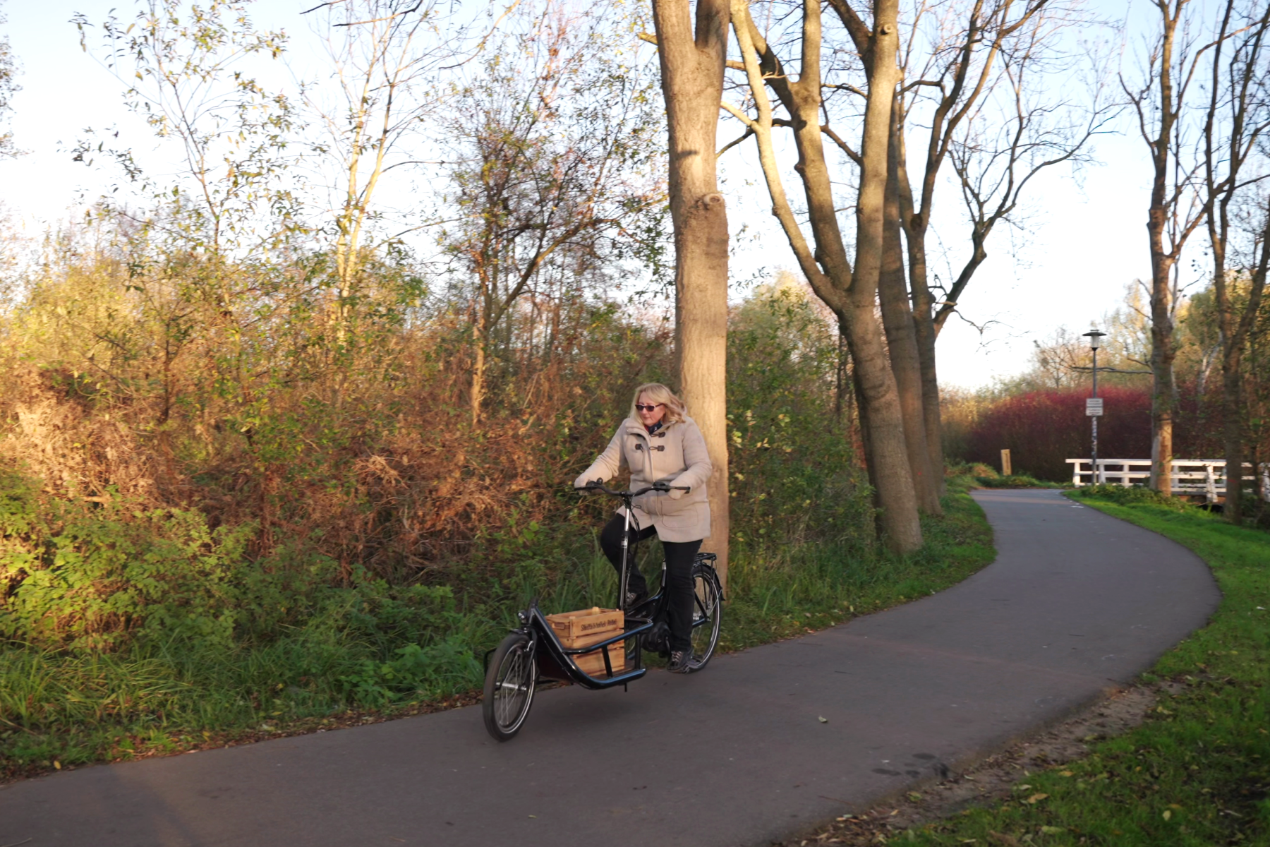 Frau fährt auf einem Lastenrad mit einer Bücherkiste