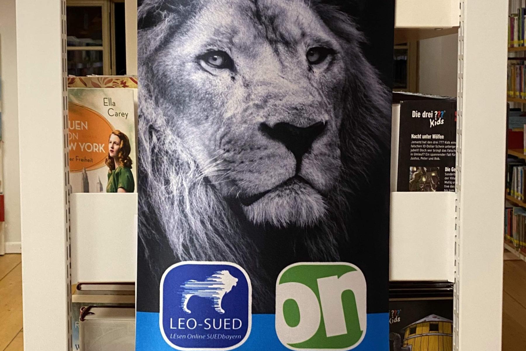 Plakat zur Leo-Onleihe in der Gemeindebücherei Weichering, oben ein großer Löwenkopf, untern App-Symbole