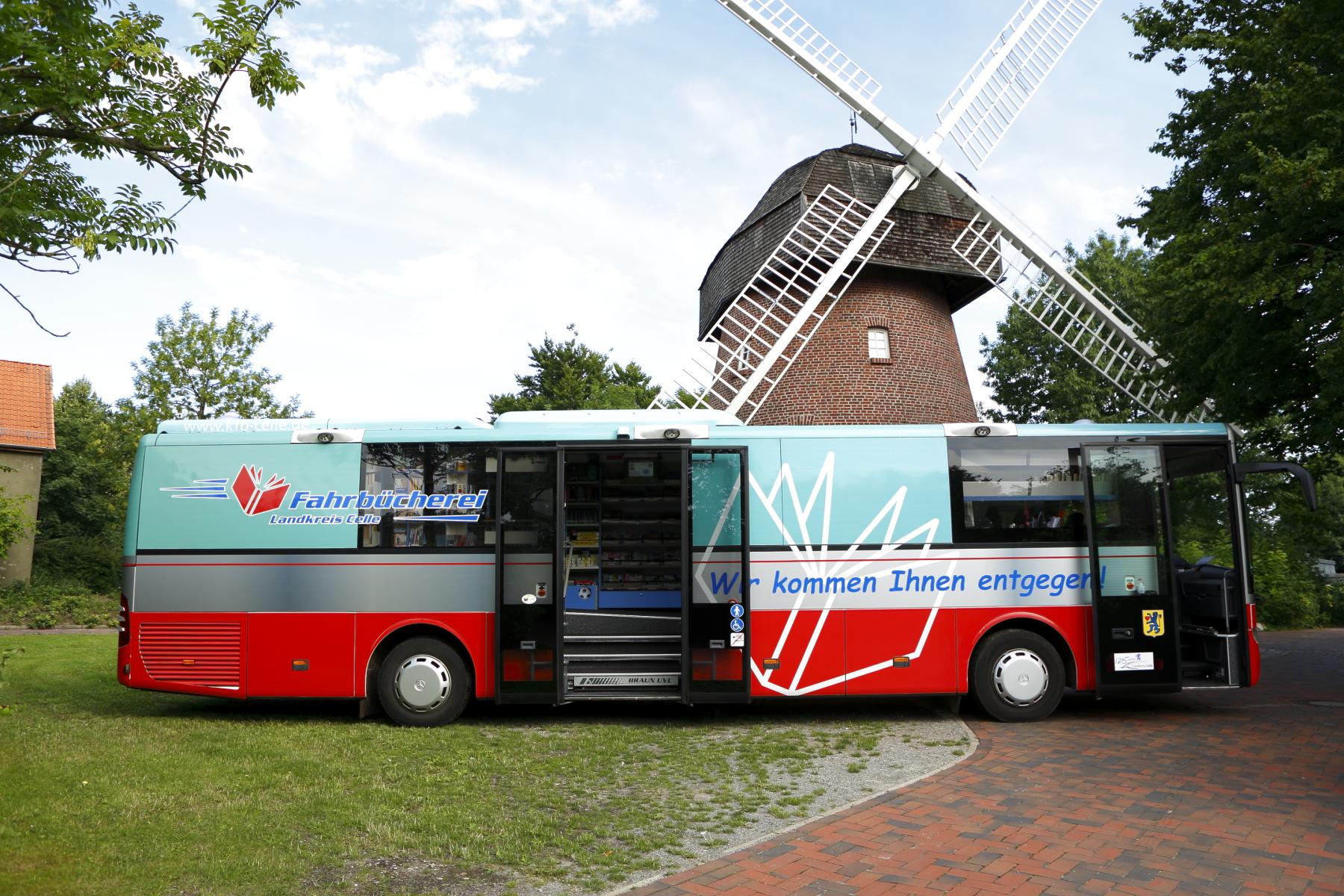 Rot-blauer Bücherbus vor einer Windmühle