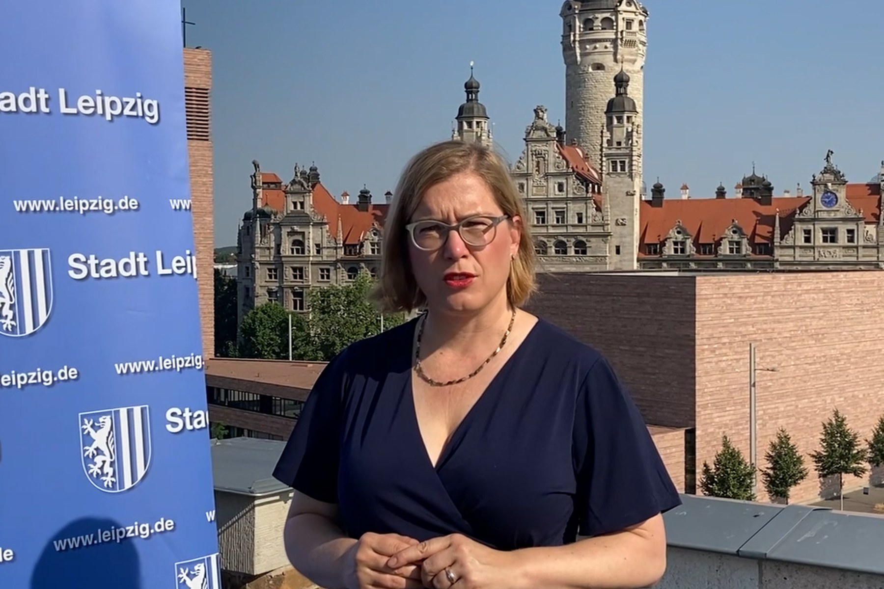 Frau Dr. Skadi Jennicke, Bürgermeisterin für Kultur Leipzig, steht neben einem Roll-up der Stadt Leipzig mit der Stadt im Hintergund.
