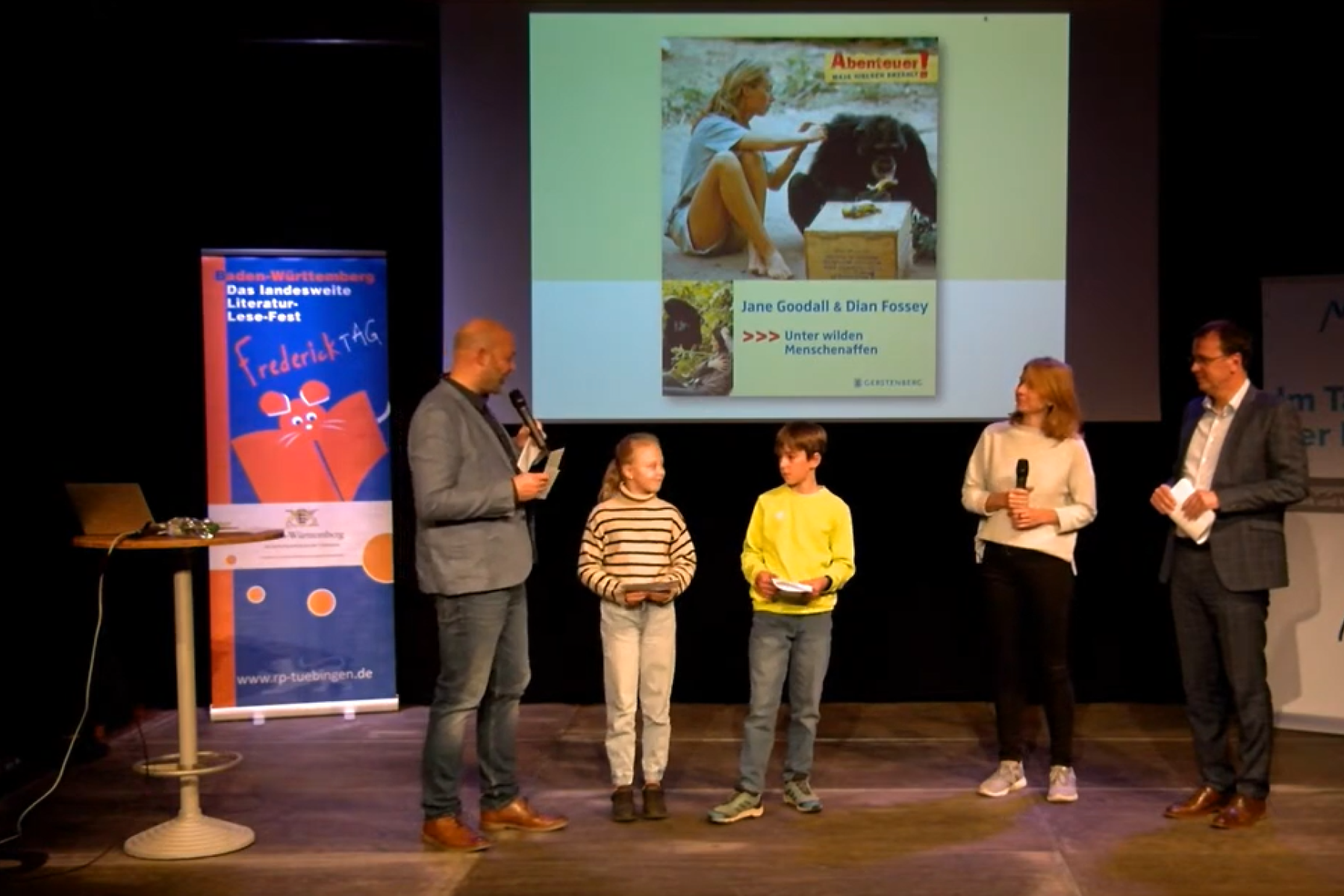 Zwei Kinder und drei Erwachsene stehen auf der Bühne.