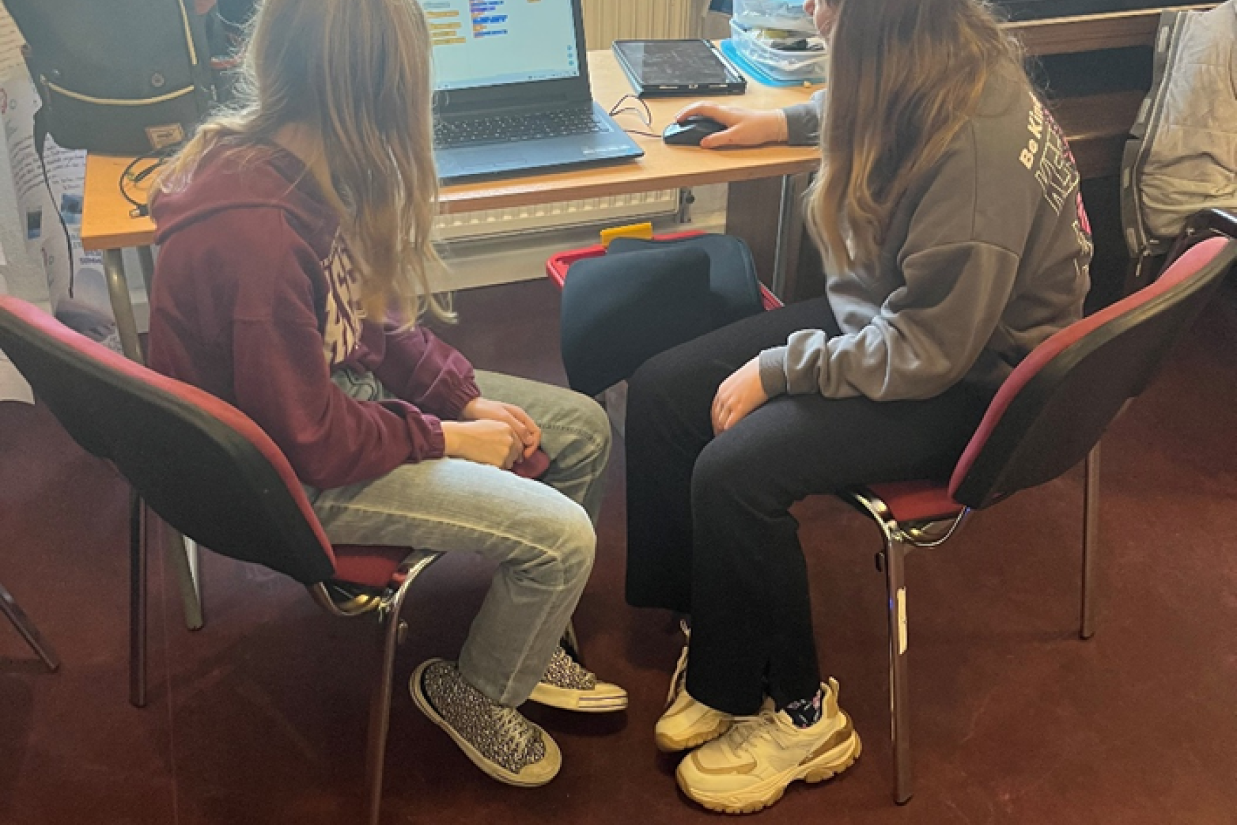 Zwei Mädchen sitzen am Laptop und programmieren einen Roboter.