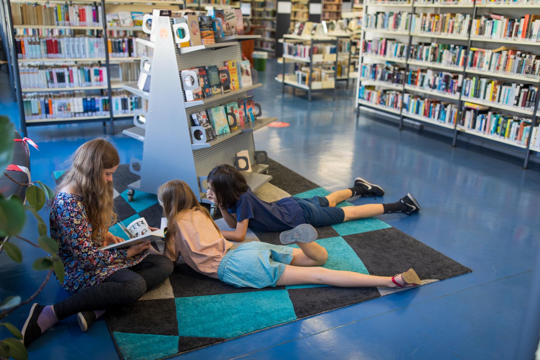 Kinder liegen in der Bibliothek und lesen