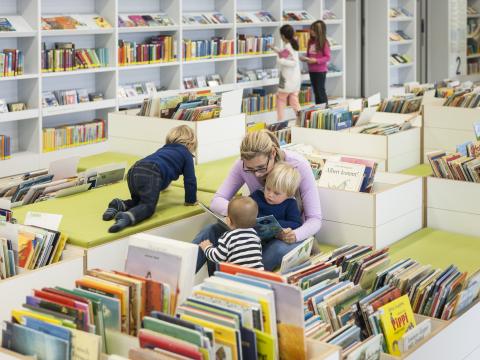 Vorlesesituation in der stadtbibliothek Stuttgart, bei der eineFrau ihren Kindern vorliest.