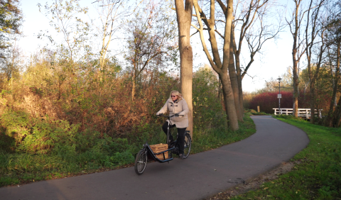 Frau fährt auf einem Lastenrad mit einer Bücherkiste