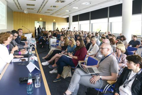 Eine Podiumsdiskussion in Messeräumen mit vier Diskutantinnen und der Raum ist voll mit Zuhörerinnen.