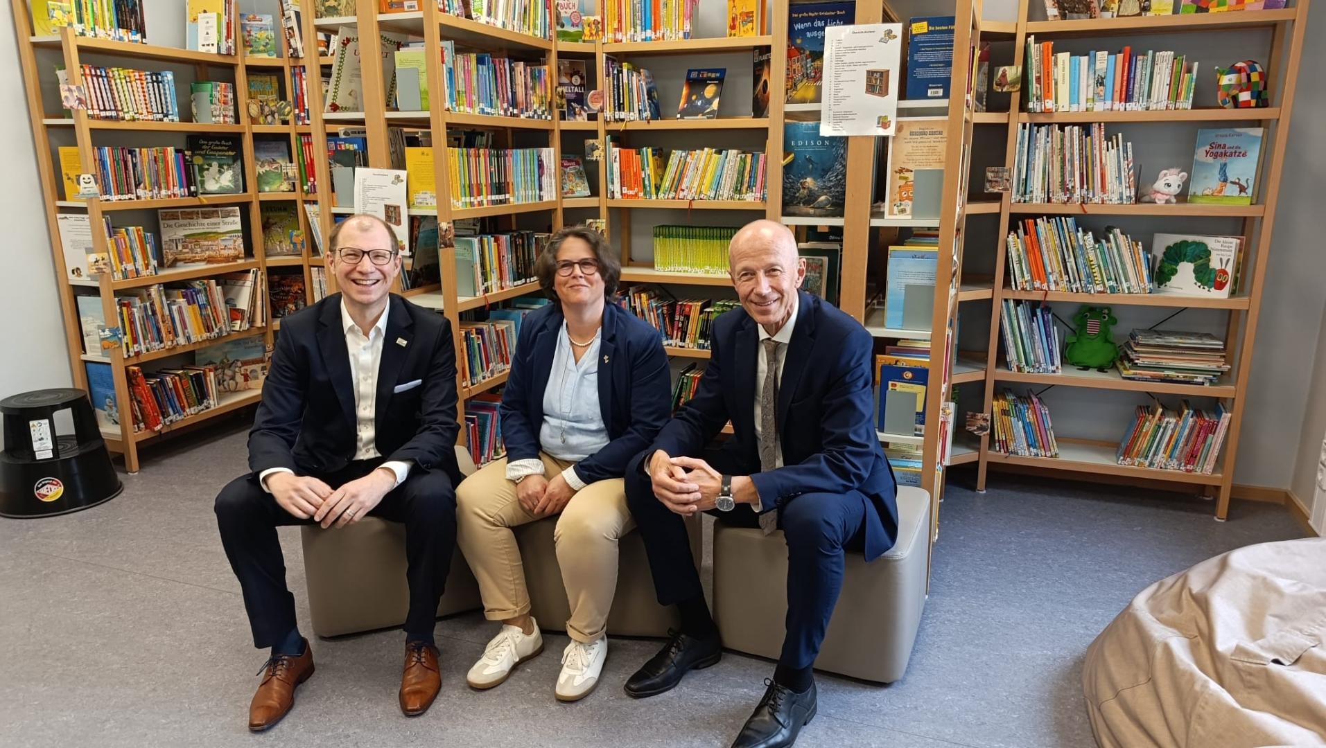 Drei Personen sitzen in der Bibliothek