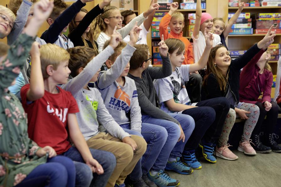 Schülergruppe in der Bibliothek meldet sich