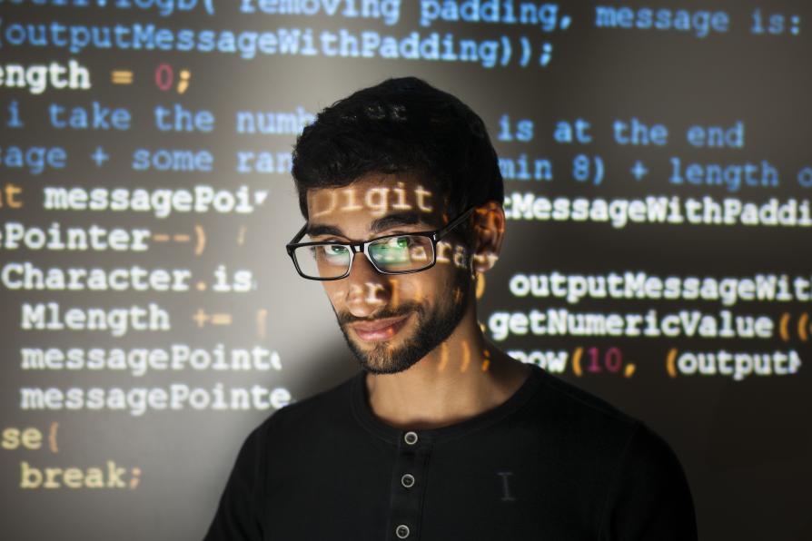 Junger Bibliothekar mit Brille mit Code-Projektionen auf dem Gesicht