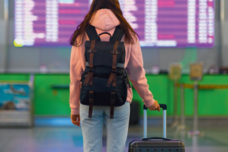 Frau von hinten mit Rucksack und Koffer