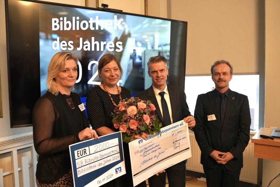 Preisträger und Juroren mit Urkunde, einem Check und Blumen 