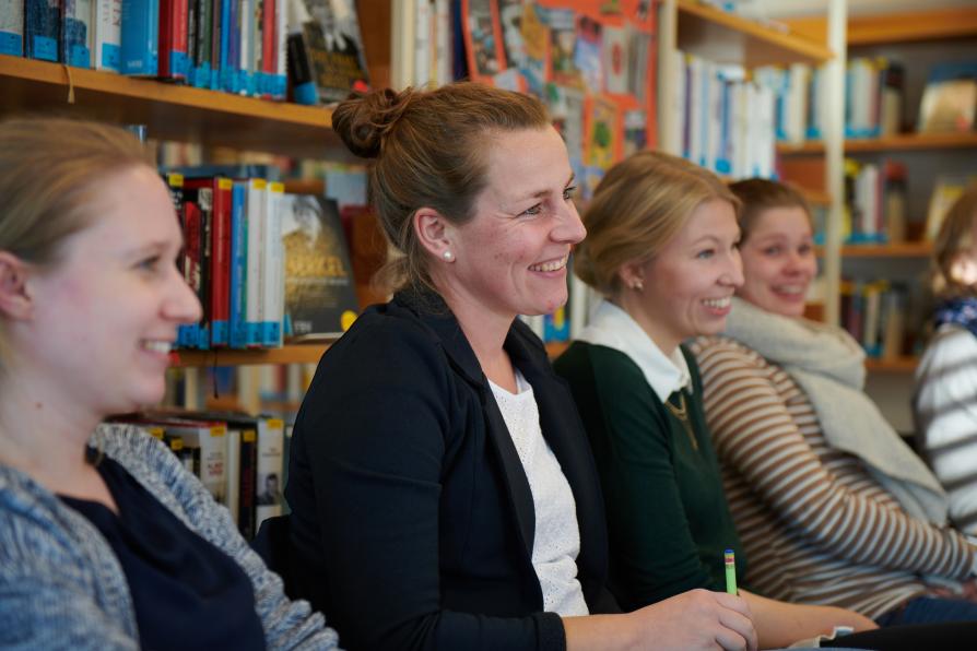 Mehrere Frauen sitzen in der Bibliothek und freuen sich.