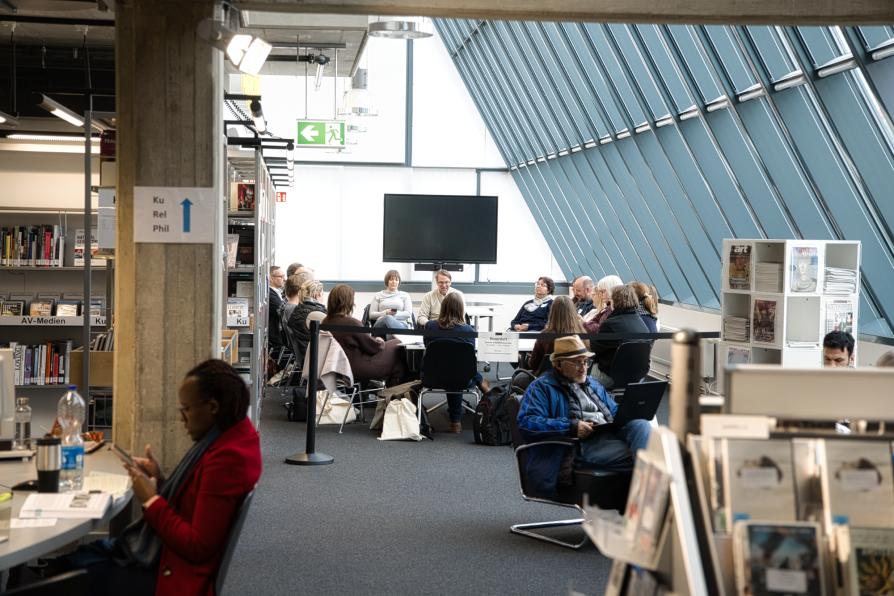 Eine Gruppe sitzt in der Bibliothek.