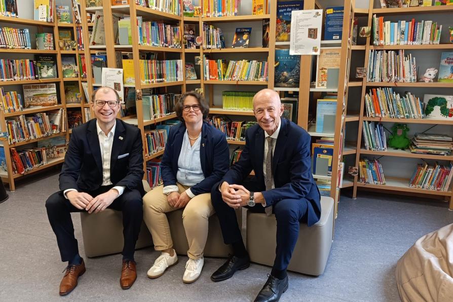 Drei Personen sitzen in der Bibliothek