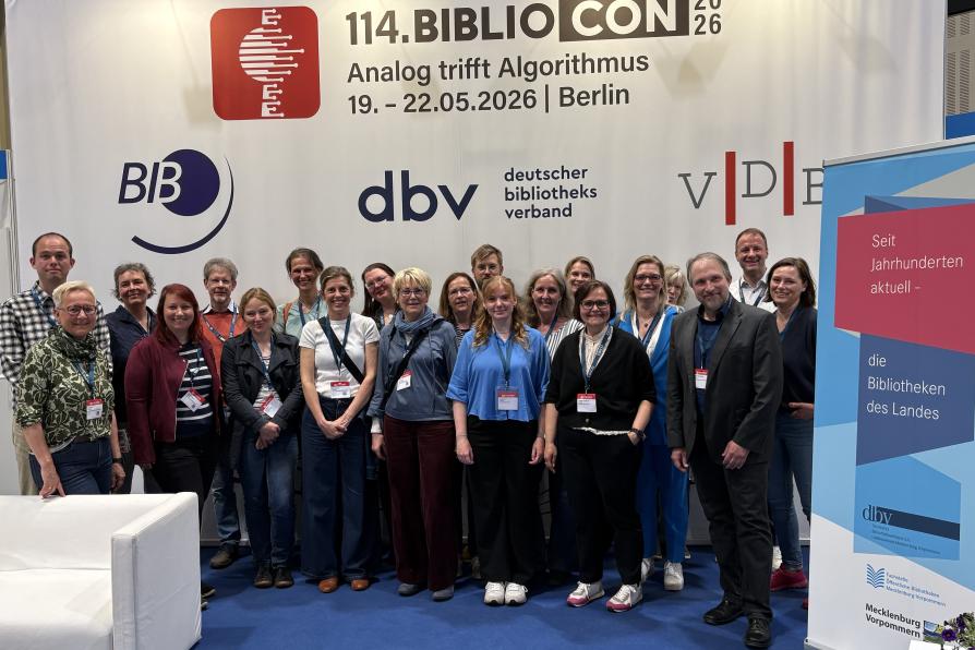 Vor einer Wand mit vielen Logos stehen 20 Personen und lächeln in die Kamera.