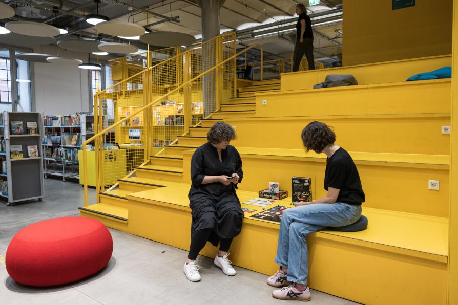 Zwei Frauen spielen in der Bibliothek ein Brettspiel