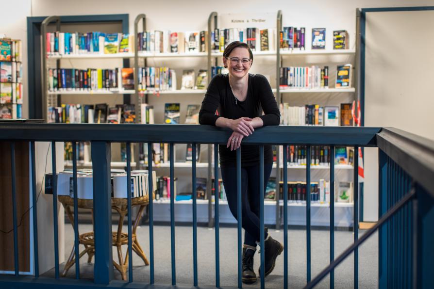 Eine Frau lehnt sich auf ein Geländer in der Bibliothek